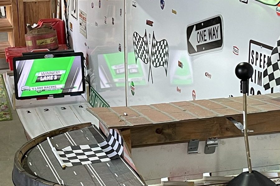The four lanes of Legend's Dragway with the winner screen lit and a checkered flag on the barrel.